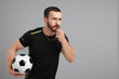 © New Africa - Young man with soccer ball blowing whistle on grey background, space for text