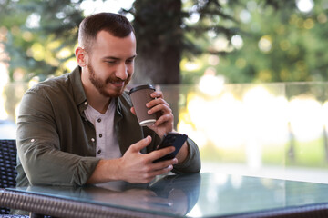 Poster - Handsome man using smartphone and drinking coffee at outdoor cafe