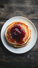 Perfect for brunch: fluffy golden brown pancakes with sweet jam on a rustic table, ideal for cafes