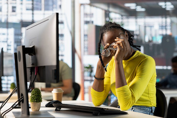 Tired programmer having strained eyesight from overworking, doing software quality assurance. Woman at work removing eyeglasses to rub eyes, looking at PC screen for too long while inspecting coding