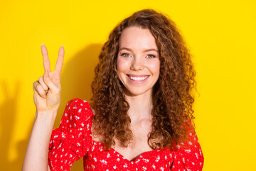 Poster - Photo of cheerful pretty lady dressed red blouse showing v-sign empty space isolated yellow color background