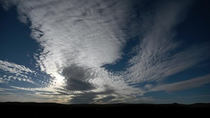 Wall Mural - time lapse looking towards the sun of dramatic morning clouds above distant hills