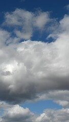 Wall Mural - vertical format time lapse of white summer clouds moving in a blue sky