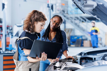 Mechanic in car service ordering new engine for damaged vehicle using laptop. Employee next to client looking online for components to replace old ones in malfunctioning automobile