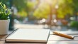 © Lens Legacy - A spiral notebook lies open on a wooden café table under bright sunlight, paired with a pencil and potted plant, infusing the scene with relaxed creativity.