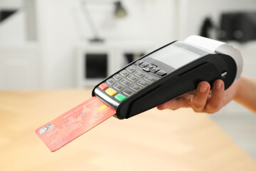 Cashier taking credit card payment with POS machine indoors, closeup