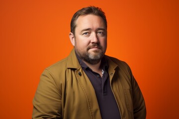 Portrait of a handsome bearded man in a yellow jacket on an orange background