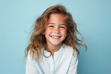 Portrait of a smiling little girl with long blond hair on a blue background