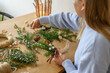 © Franci Leoncio - Person arranging natural decorations for a Christmas wreath