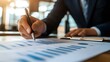 © WisChi - Businessman analyzing financial data with pen and charts