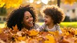 © Tessa - Mother and child laughing together in autumn leaves