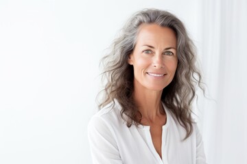 Portrait of a beautiful mature woman smiling at the camera while standing against white background