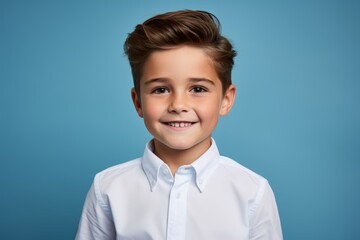 Portrait of a smiling little boy in a white shirt on a blue background