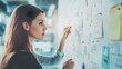 © sungedi - Young Woman Analyzing a Whiteboard with Sticky Notes and Drawings