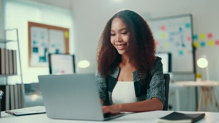 Aufkleber - Young manager is sitting at her desk, smiling as she types on her laptop. She is surrounded by office supplies and appears to be in a good mood