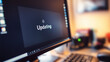 © Dai - Close-up of computer screen showing software update progress bar with 'Updating' text, keyboard and mouse visible in blurred background, modern technology and digital transformation concept.