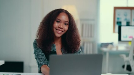 Aufkleber - Smiling african american manager with curly hair works on her laptop in a bright office. The atmosphere reflects professionalism and confidence, showcasing a successful business environment