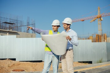 team of building experts with drawings inspecting new development site