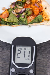 Wall Mural - Glucose meter for sugar level control and piece of vegetarian pizza. Nutrition and eating fast food during diabetes