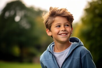 Portrait of a smiling boy in a blue hoodie outdoors.