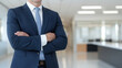 © supattra - Businessman in suit standing, close up of upper body, office background, blurred background.