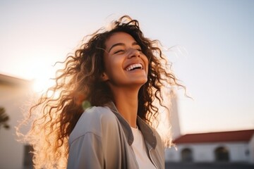 portrait of a beautiful young woman with curly hair smiling outdoors at sunset