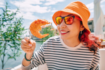 Wall Mural - Close-up of a woman enjoying a delicious shrimp dish at a seafood restaurant, showcasing gourmet cuisine.