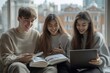 © Yash - Young guy and Asian female student laughing and reading book together while their Hispanic female classmate surfing net on laptop sitting on windowsill at, Generative AI