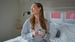 © stockbusters - Relaxed lady holding cup beverage on comfortable bed at weekend morning closeup.