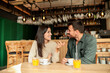 © BGStock72 - Couple enjoying at a cozy cafe with warm drinks and laughter in a vibrant, modern setting on a sunny afternoon