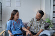 © Tj - Young female doctor is comforting her senior patient during a home visit while holding a tablet and listening to his concerns