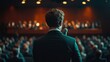 © Rajiv - Backview of a Stylish Young Businessman in a Dark Crowded Auditorium at a Startup Summit. Young Man Talking to a Microphone During a Q and A session. Entrepreneur Happy with Event