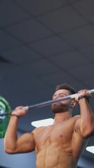 Wall Mural - Bodybuilder raising barbell over his head. Young shirtless sportsman exercises his maintain muscle in gym. The active man lifting a barbell. Handsome athlete doing weight lifting. Vertical video