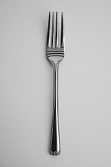 Simple shiny fork placed on a gray background highlighting its elegant design and symmetry