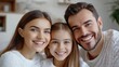 © Nathan - A smiling Caucasian family of three, featuring a mother, father, and daughter, share a joyful moment in a cozy living room.