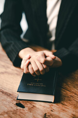 Cropped view of young woman praying with bible on table Confession concept Pray and talk with God