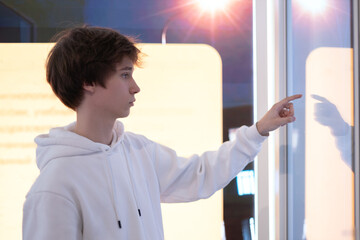 Young man using interactive touchscreen kiosk - scrolling and touching. Education, and technology concept