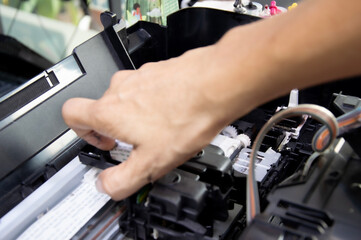 Poster - a technician is fixing a stuck printer mechanism.
