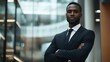 © Eric - A portrait of a black businessman posing confidently with crossed arms in a corporate environment.