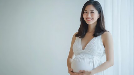 A happy pregnant woman gently cradles her baby bump, wearing a flowing white dress, standing in a bright, airy room with soft natural light.