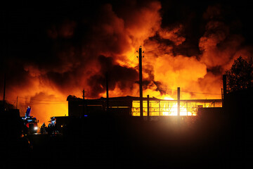 Burning industrial building. Big blaze and smoke at night