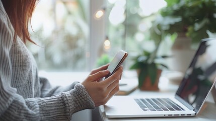 Close-Up asian business Person Using Smartphone in Minimalist Workspace with Laptop, Digital modern office, surfing the internet, global internet networking, social media concept with Natural Light