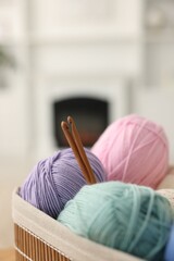 Poster - Many colorful yarns and crochet hooks in basket on blurred background, closeup. Space for text