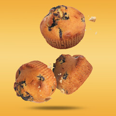 Wall Mural - Delicious blueberry muffins falling on golden background