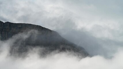 Wall Mural - time lapse of rounded rocky mountain surrounded by clouds and mist, banff
