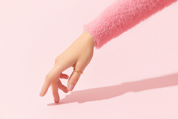 Poster - Beautiful groomed womans hand with pink matte nail design on a pink background. Manicure, pedicure beauty salon.