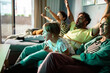 © Marko Geber - Excited family watching TV and cheering on the couch