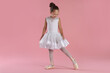 © New Africa - Little ballerina practicing dance moves on pink background