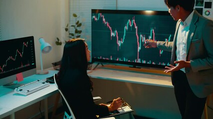 Aufkleber - Male financial advisor gestures while explaining stock market fluctuations to a female client in a formal office setting at night, fostering an engaging discussion about investment strategies