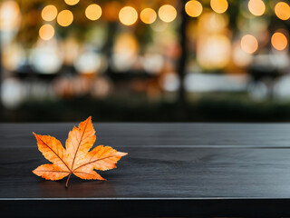 Poster - Bright orange maple leaf lying on empty black table during autumn